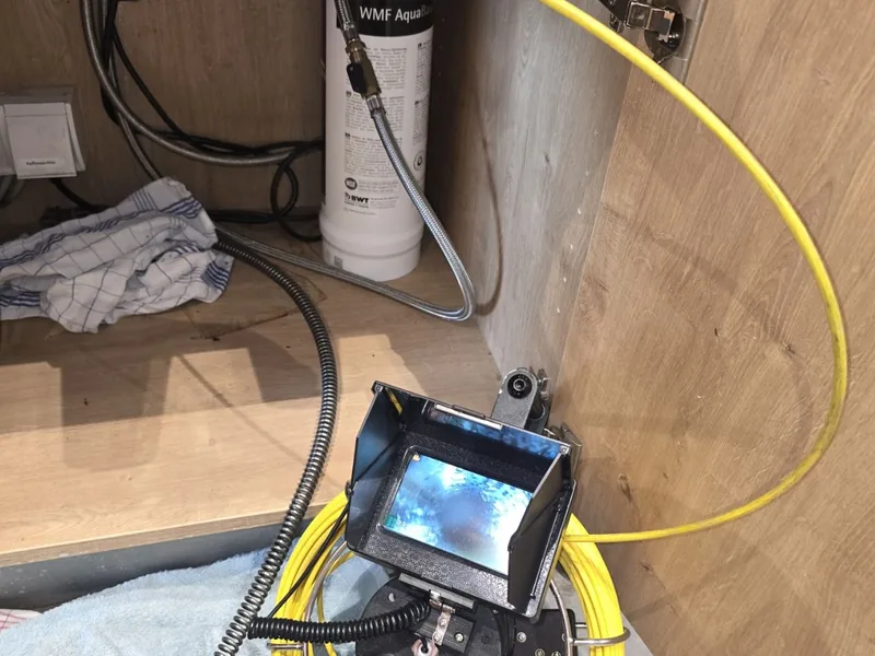TV-Rohrinspektion unter der Küchenspüle, Monitor zeigt das Rohrinnere